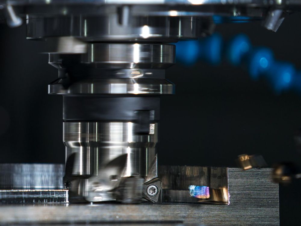 Close-up of an indexable face mill cutting a steel part inside a CNC machine